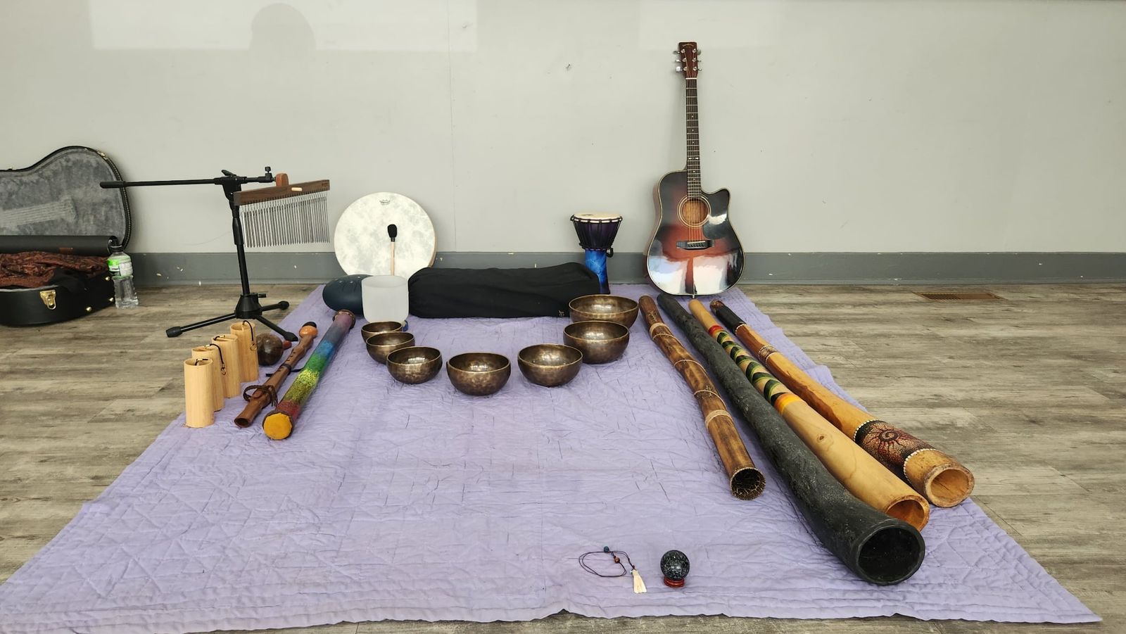 Singing bowls, didgeridoos, frame drum and chimes laid out for a sound healing session