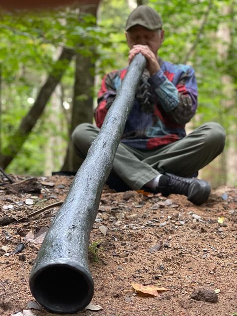 Low-angle view along a didgeridoo while playing cross-legged